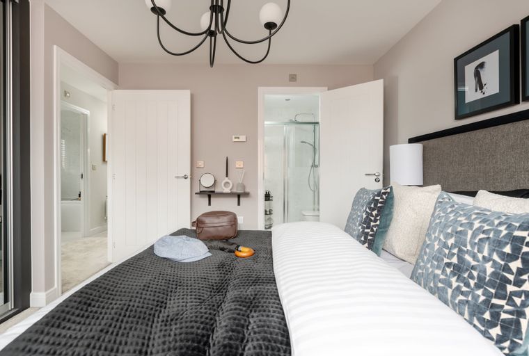 A bedroom with a bed, pillows, and an open door leading to a bathroom.