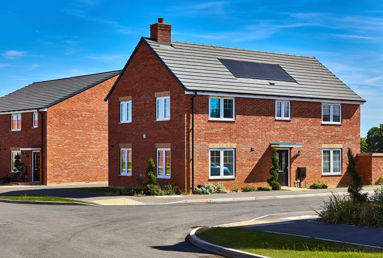 A pair of modern brick houses with white-framed windows and grey tile roofs under a clear blue sky.