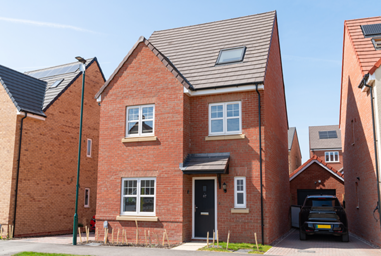 A red brick house with white-framed windows and a dark grey front door.