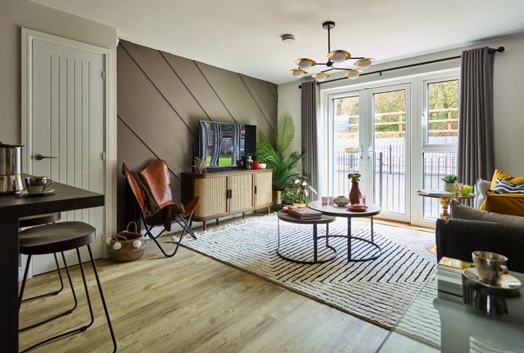 A living room with a television, a media console, a butterfly chair, and coffee tables.