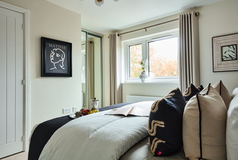 A bedroom with a bed, pillows, a window, and artwork on the wall.