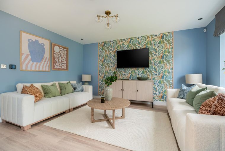 A living room with two white sofas, a coffee table, a television, and a rug.