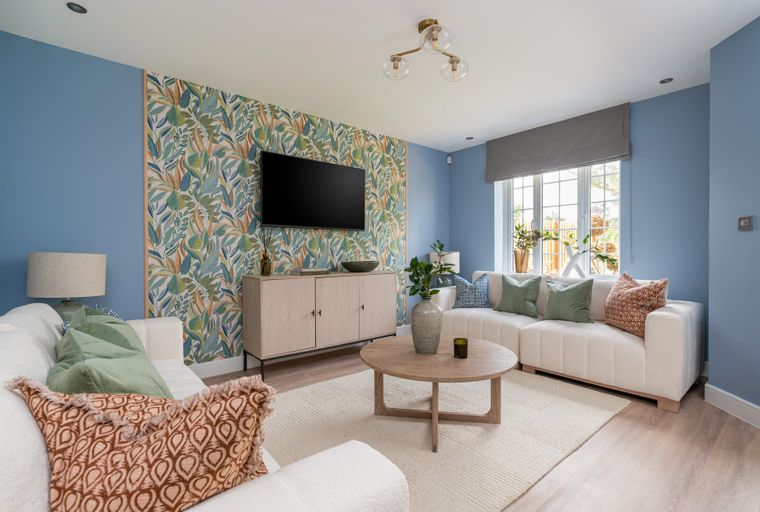 A living room with a patterned accent wall, sofas, a coffee table, and a television.