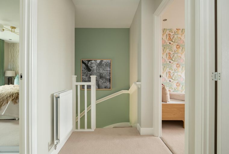A hallway with a staircase, a radiator, and doorways to two bedrooms.