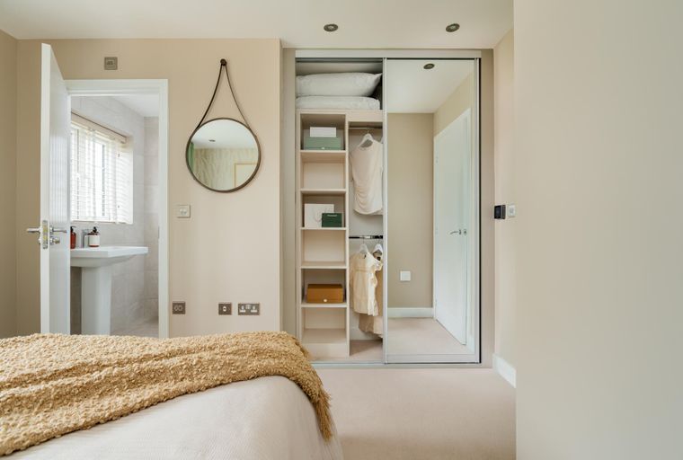 A bedroom with a bed, a wardrobe, a mirror, and a doorway to a bathroom.