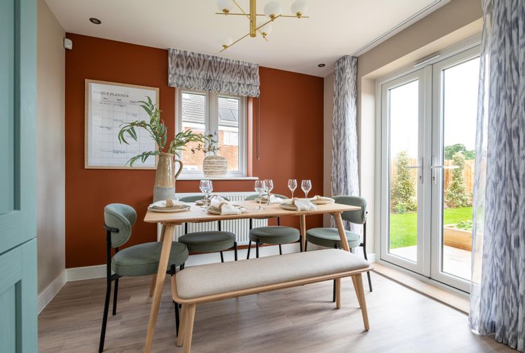 A dining room with a wooden table, chairs, a bench, and a chandelier.