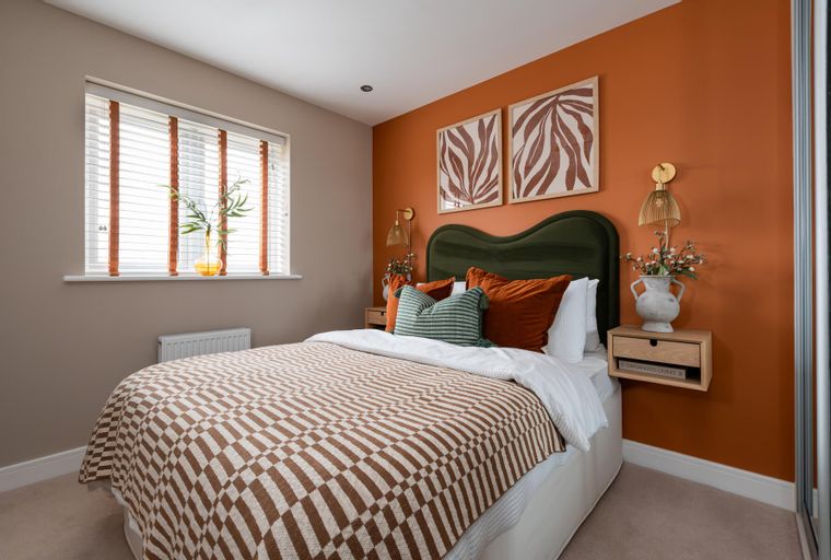 A bedroom with a bed, headboard, pillows, and a wall with artwork.