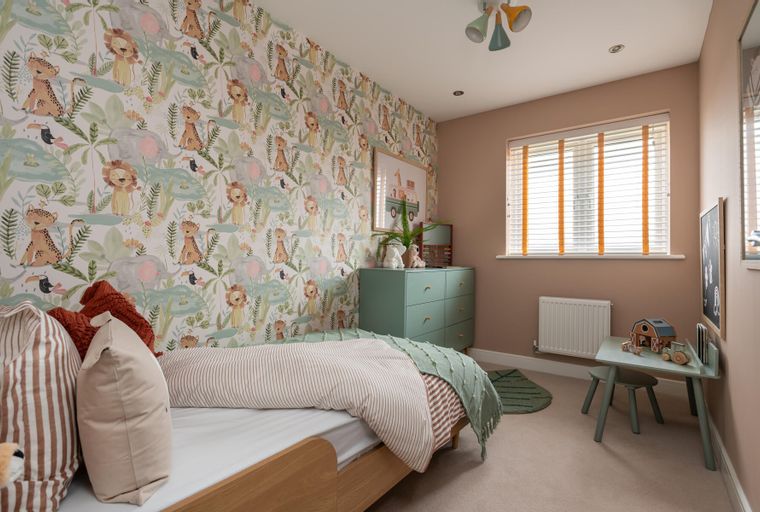 A children's bedroom with jungle-themed wallpaper, a bed, and a dresser.