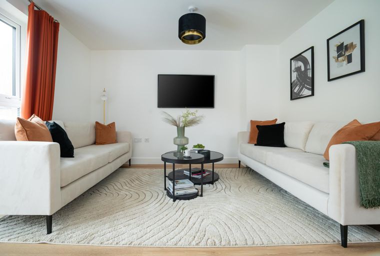 A living room with two sofas, a coffee table, a TV, and abstract art.