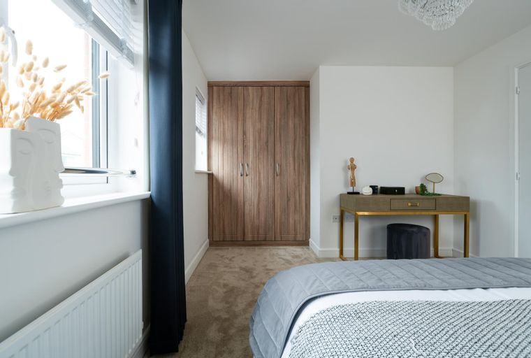 A bedroom with a bed, a dressing table, and a wardrobe.
