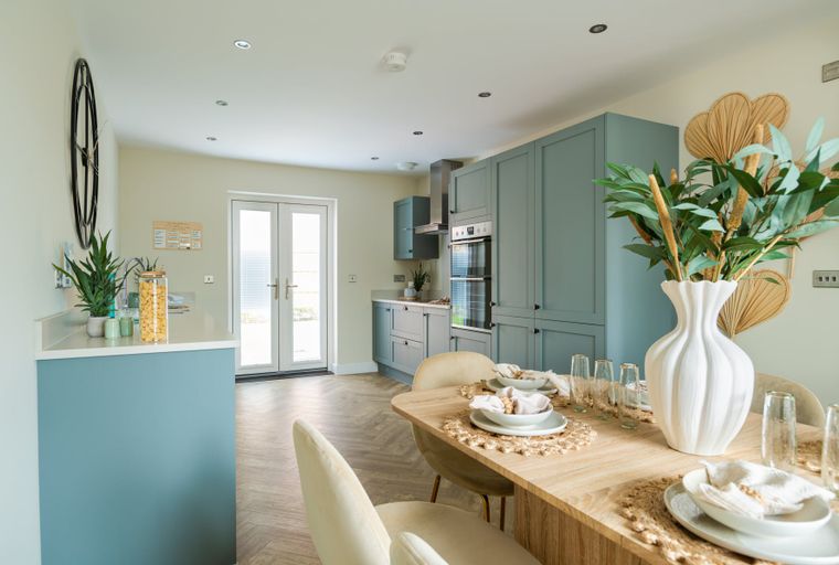 A kitchen and dining area with sage-green cabinets, a dining table, and chairs.