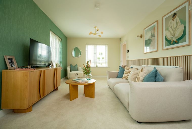 A living room with a sofa, armchair, coffee table, media console, and television.