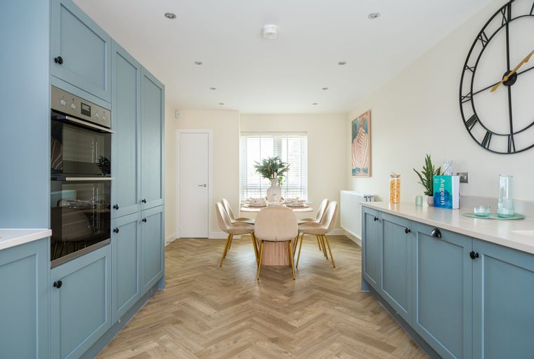 A kitchen and dining area with blue cabinets, a round dining table, and chairs.