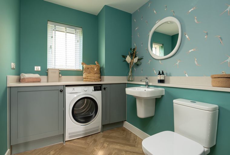 A laundry room with a washing machine, dryer, sink, and toilet.