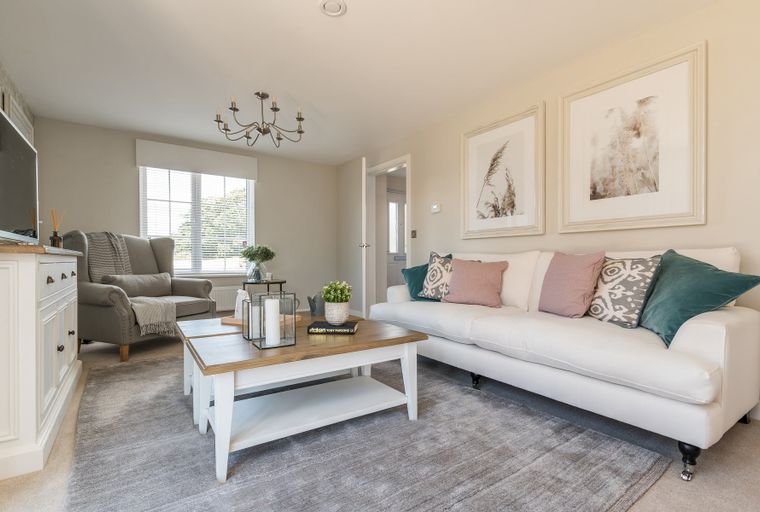 A living room with a white sofa, armchair, coffee table, and artwork.
