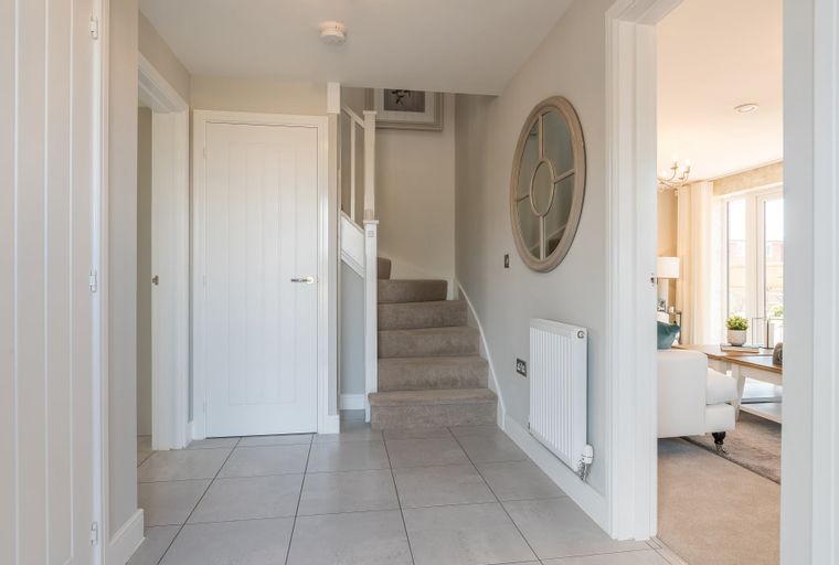 A hallway with a staircase, white doors, and a round mirror.
