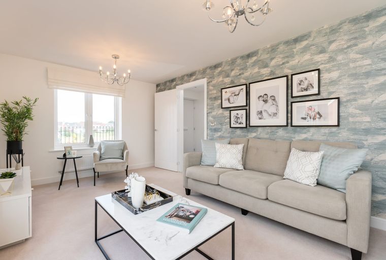 A living room with a sofa, armchair, coffee table, and framed pictures on the wall.