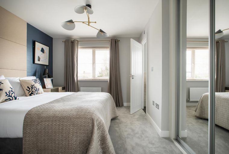 A bedroom with a bed, pillows, a throw blanket, curtains, a window, a ceiling light, and a mirrored wardrobe.