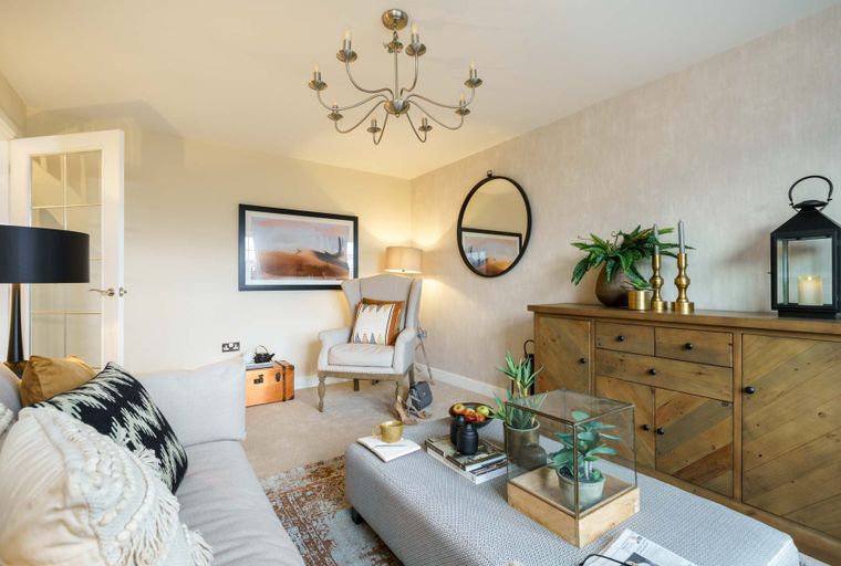 A living room with a sofa, armchair, and a wooden sideboard.
