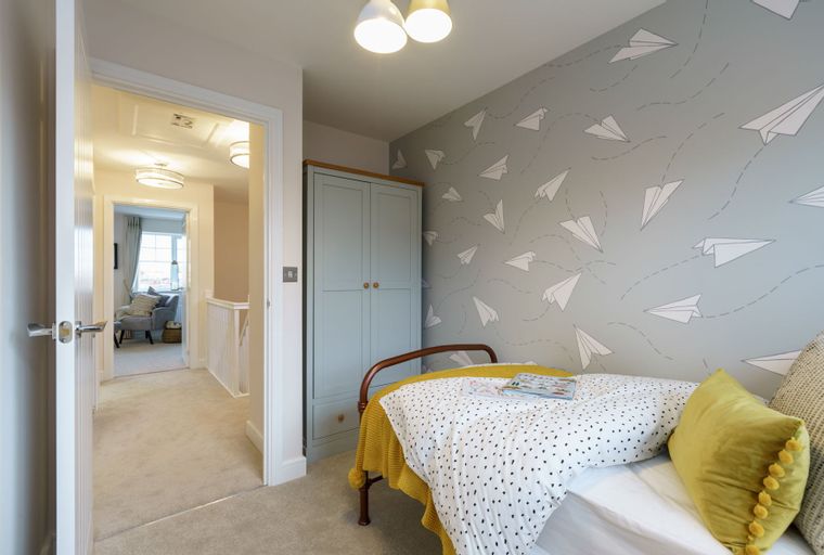 A bedroom with a bed, a wardrobe, and paper airplane wallpaper.
