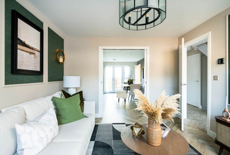 A living room with a white sofa, artwork, and a coffee table.