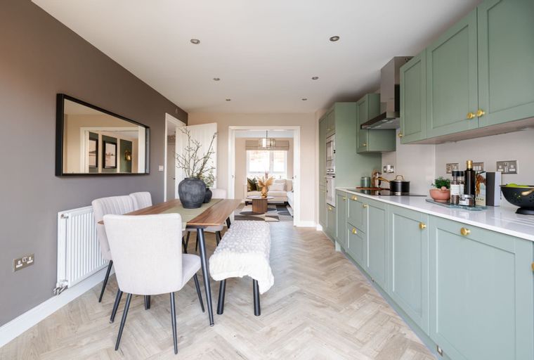 A dining area and kitchen with green cabinets and a wooden table.