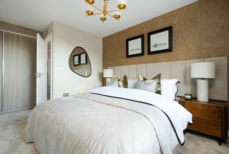 A bedroom with a bed, lamps, and a mirror.