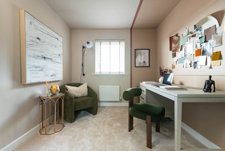 A home office with a desk, chair, armchair, and artwork.