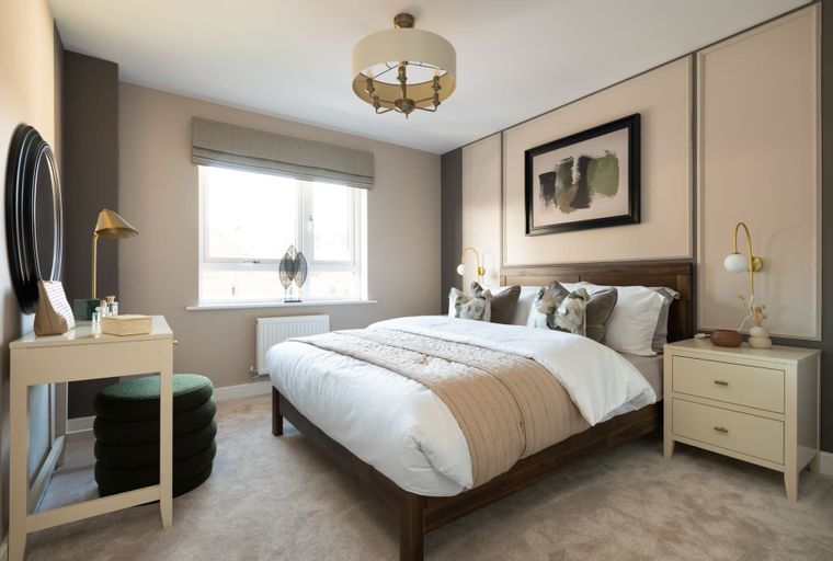 A bedroom with a bed, nightstands, a vanity, and a window.