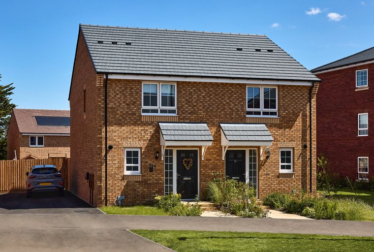 A pair of brick semi-detached houses with black front doors and white-framed windows under a grey tiled roof.