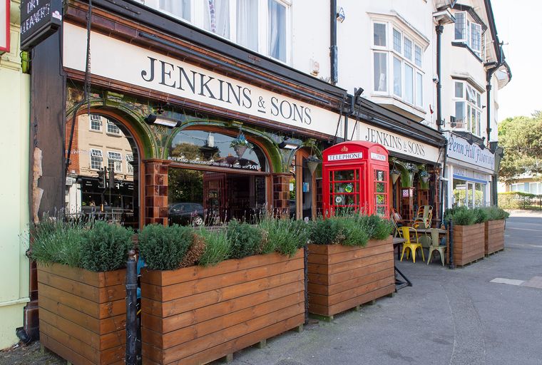 A storefront with a red telephone box and outdoor seating.