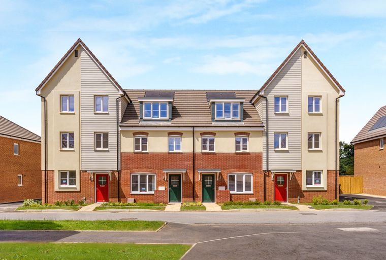 A row of new townhouses with red and green front doors under a blue sky.