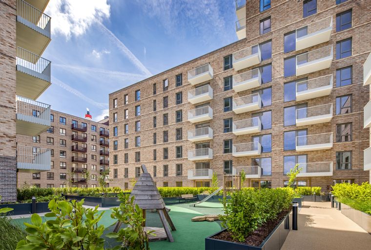 A modern apartment building with balconies and a playground in the courtyard.