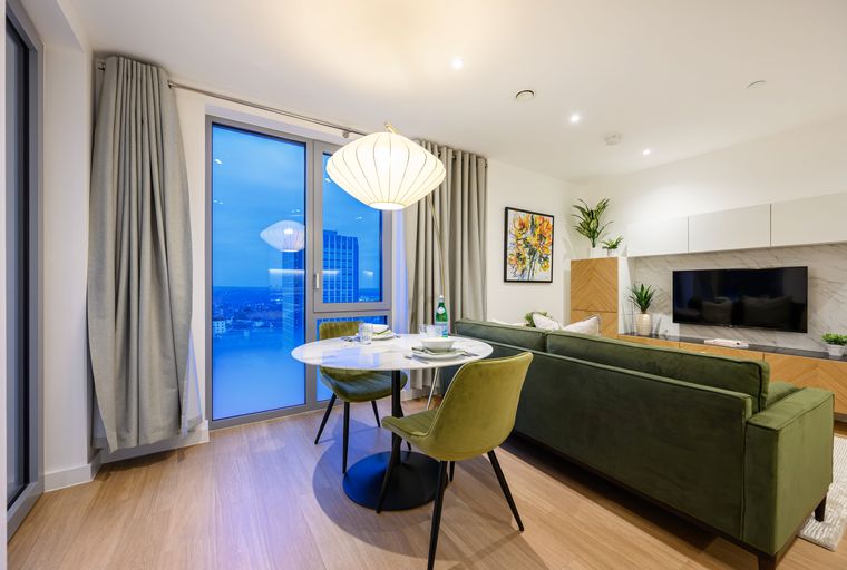 A dining area and living room with a sofa, table, chairs, and a television.