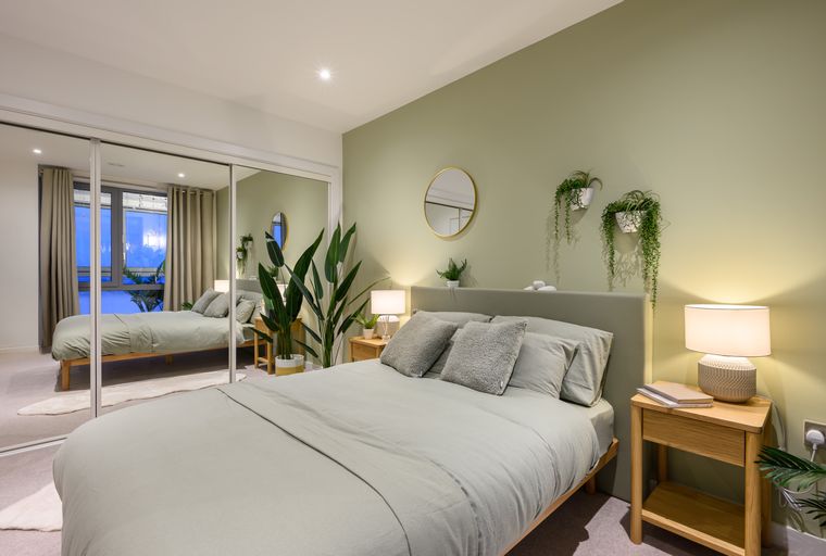 A bedroom with a bed, nightstands, lamps, and a mirrored wardrobe.