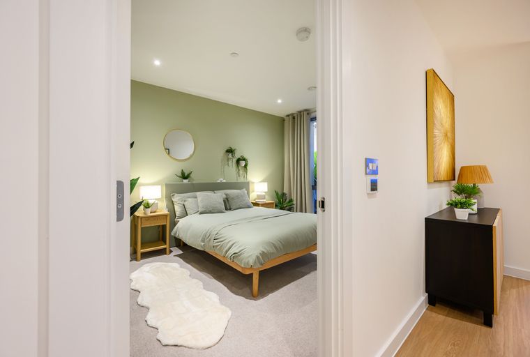 A bedroom with a bed, bedside tables, lamps, and a rug.