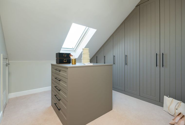 A walk-in closet with a central island dresser and built-in wardrobes.