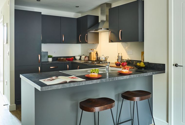 A modern kitchen with dark cabinets, a breakfast bar, and two stools.