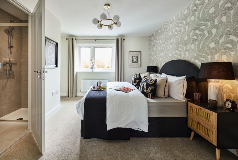 A bedroom with a bed, bedside tables, a window, and an open doorway to a shower.