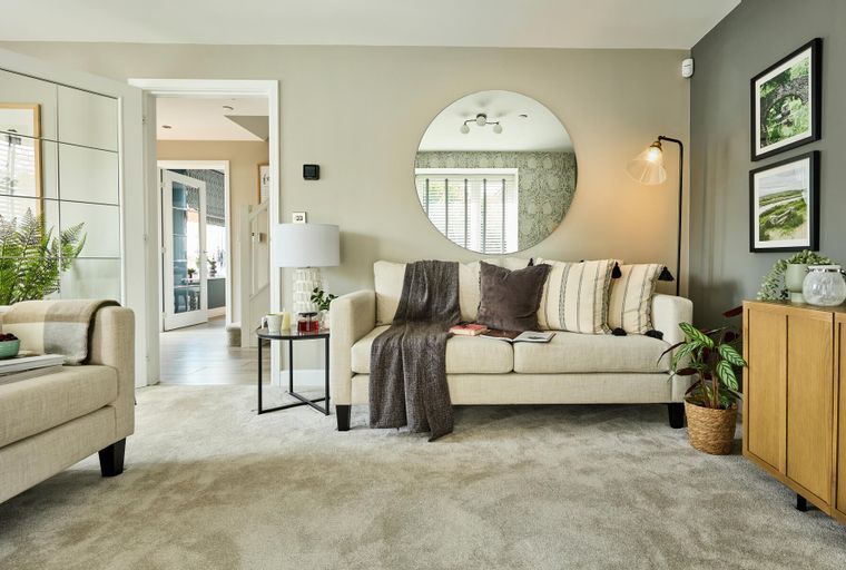 A living room with a sofa, a mirror, and a lamp.