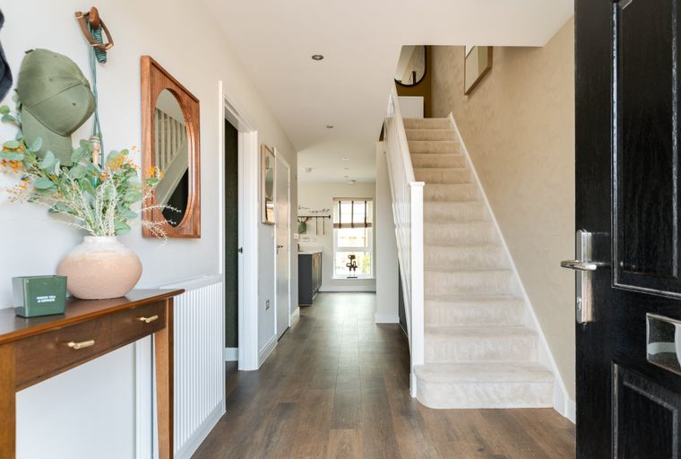 A hallway with a staircase, console table, and a door.