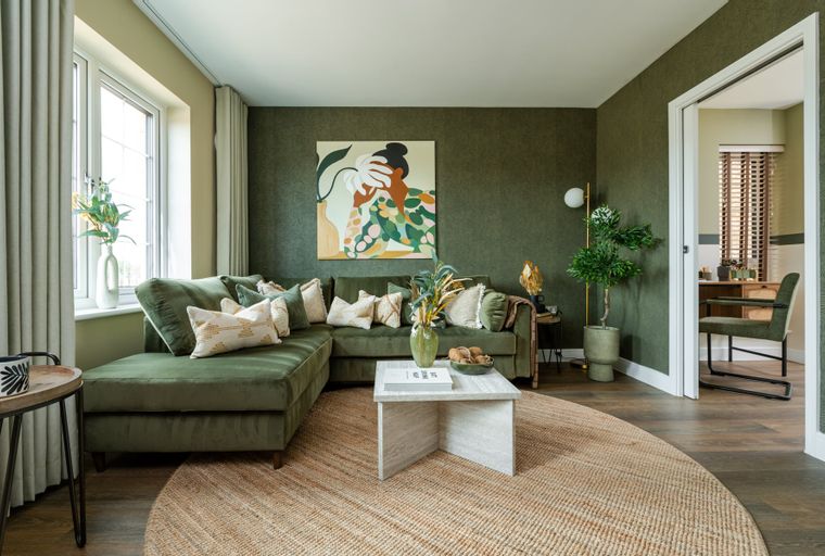 A living room with a green sectional sofa, coffee table, and abstract art.
