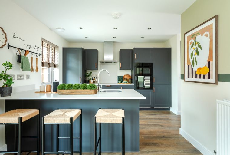 A modern kitchen with dark cabinets, a central island with bar stools, and a stainless steel range hood.