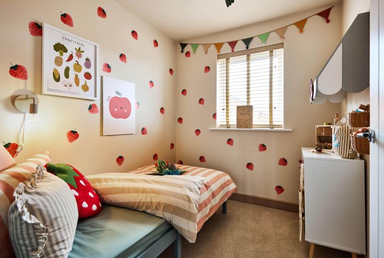 A bedroom with a bed, posters, and strawberry decals on the walls.