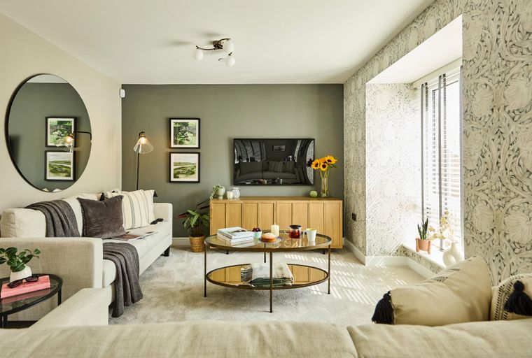 A living room with a sofa, coffee table, television, and a large mirror.