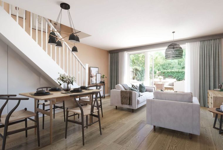 A dining area and living room with sofas and a large window overlooking a garden.