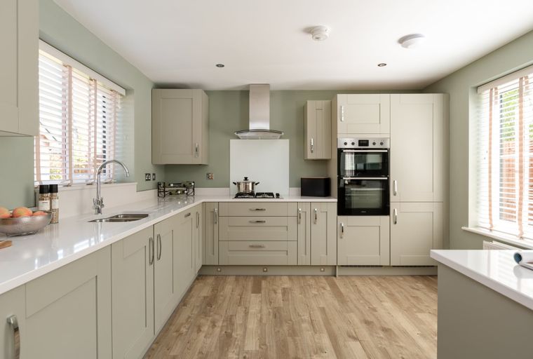 A modern kitchen with light-colored cabinets, a double oven, and a gas hob.