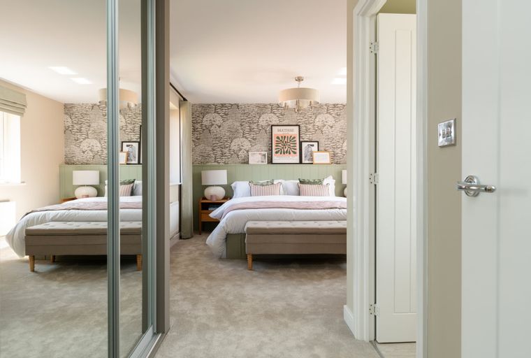 A bedroom with a bed, bedside tables, lamps, and a bench at the foot of the bed.