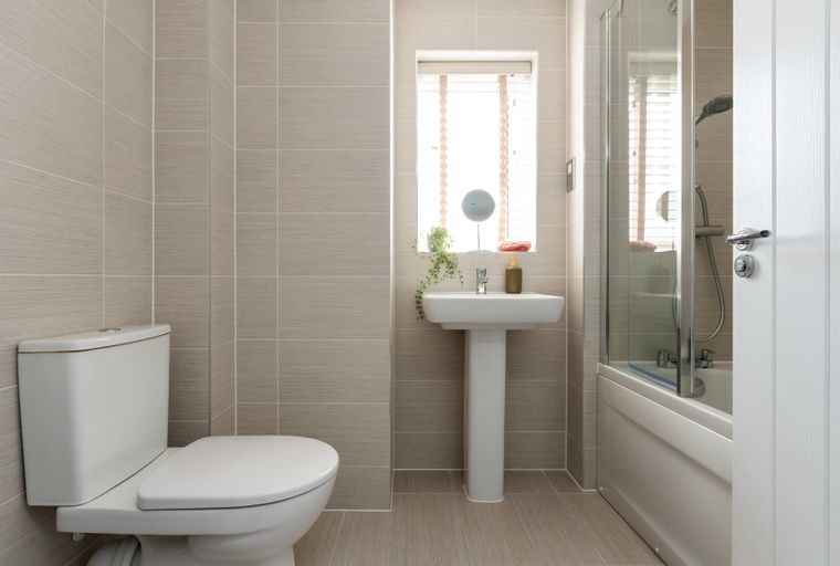 A bathroom with a toilet, sink, and shower-bath combo.