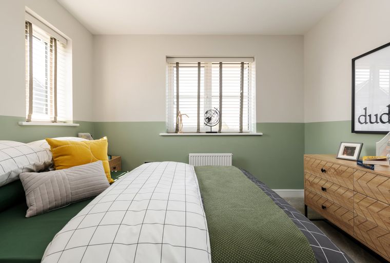 A bedroom with a bed, pillows, a dresser, and a window.